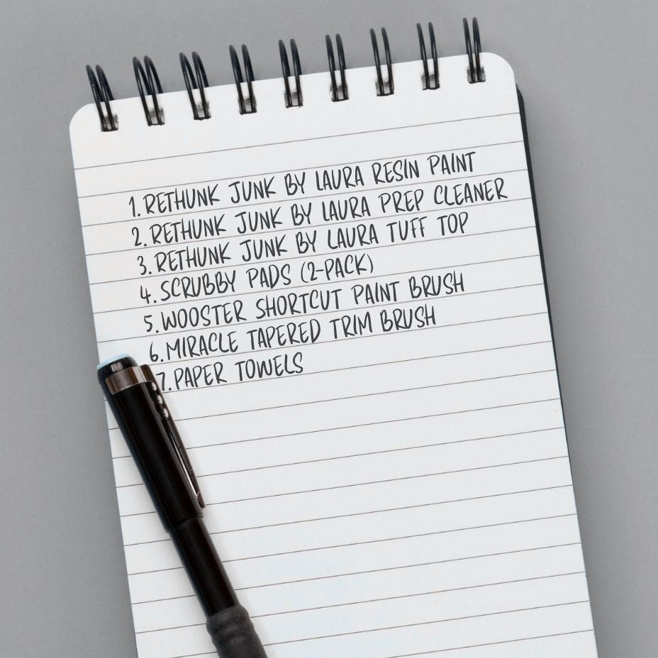 Notepad with a list of items and a pen on a gray background