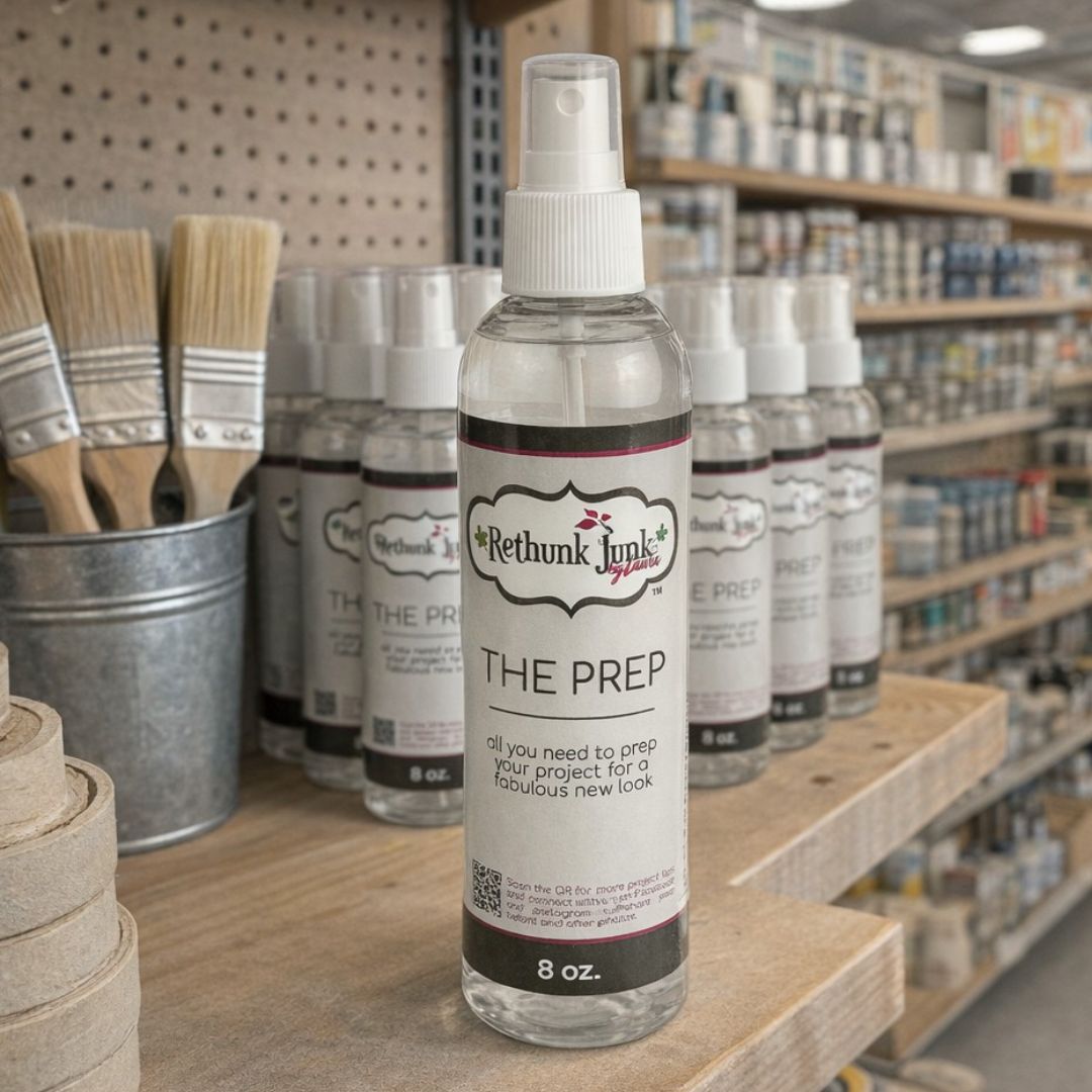 Bottle of 'The Prep' by Rethunk Junk on a wooden surface with paintbrushes and supplies in the background.